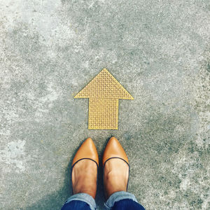 Low section of woman standing by arrow symbol