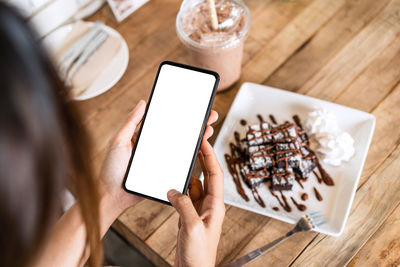 Cropped hands of woman using mobile phone on table