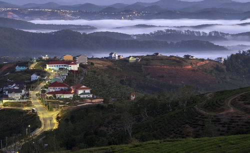 Houses on field by mountains against sky