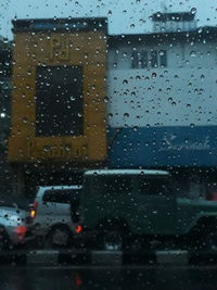 City seen through wet glass window during rainy season