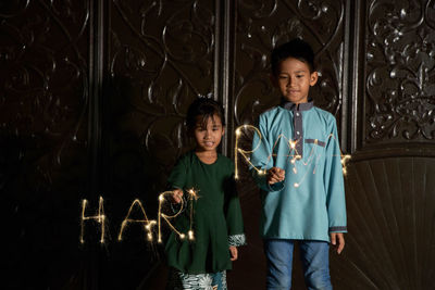 Malay siblings playing fireworks sparkler during ramadan festival 