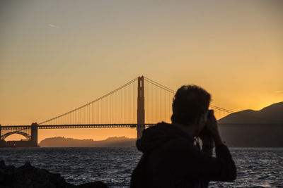 Suspension bridge over sea during sunset