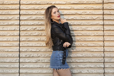 Side view portrait of beautiful woman standing by wall