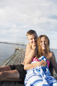 Portrait of happy couple in swimwear relaxing on pier
