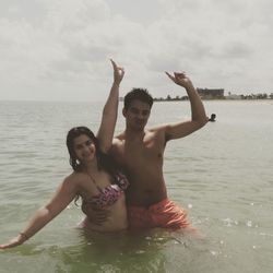 Full length of shirtless man in sea against sky