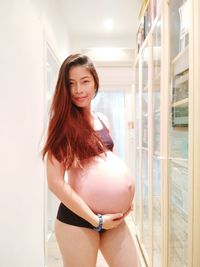 Beautiful pregnant woman standing in corridor at home