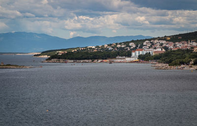 Scenic view of sea by townscape against sky