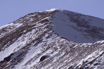 Low angle view of snowcapped mountain against clear sky