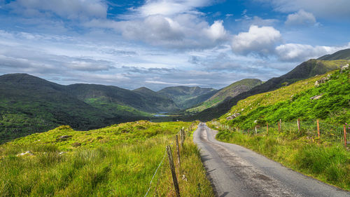 Road amidst green mountains against sky