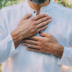 Reiki spiritual self-treatment healing session. man holding hands above the heart chakra.