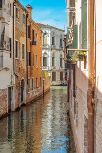 Canal amidst buildings in city against sky