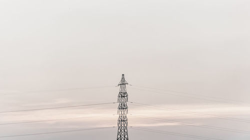 Low angle view of electricity pylon against clear sky