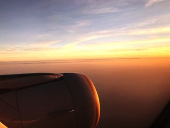 Airplane wing against sky during sunset