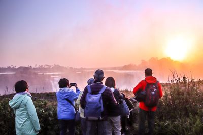 Rear view of people looking at view of sky during sunset