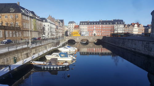 Bridge over canal by buildings in city against sky