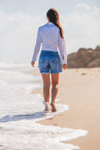 Rear view of woman walking at beach
