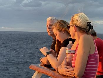 People sitting by sea against sky