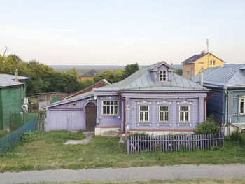 Houses on field by building against sky