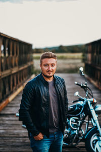 Portrait of young man standing against cars