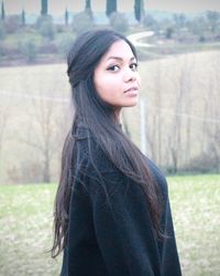 Beautiful young woman standing against tree