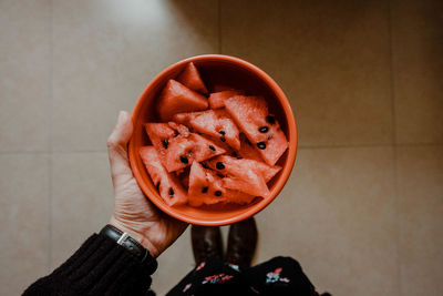 High angle view of hand holding bowl of watermelon 