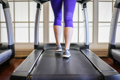 Low section of woman running on treadmill at gym