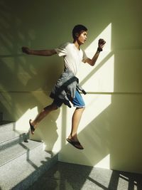 Full length of a young man jumping down stairs