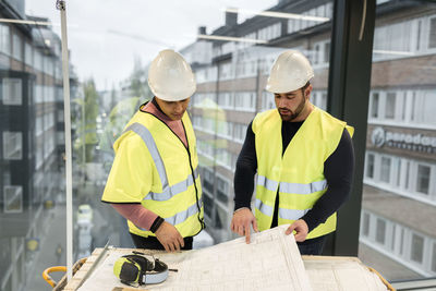 Workers reviewing blueprint at construction site