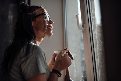 Side view portrait of a young woman holding window