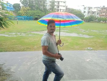 Full length of man holding umbrella standing on rainy day