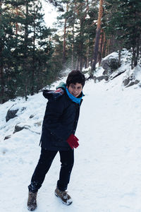 Full length of boy playing with snow in forest