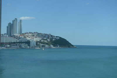 View of buildings by sea against blue sky