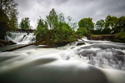 Scenic view of waterfall against sky