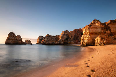 Scenic view of rocks in sea against clear sky