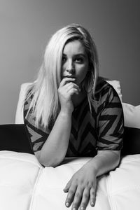 Portrait of young woman sitting on bed at home