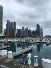 Modern buildings by river against sky in city