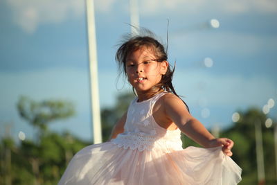 Thoughtful girl standing against sky