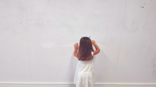 Girl standing against white wall