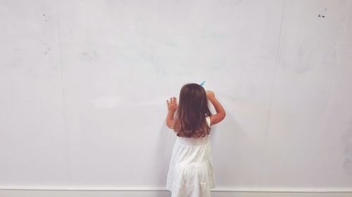 Woman standing against white wall