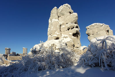 Low angle view of snow covered land against clear blue sky