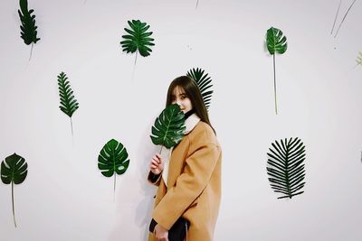 Young woman standing against plants