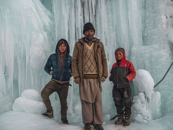 Full length portrait of friends standing on snow covered landscape during winter