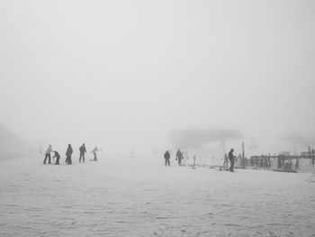 People with skis on snow covered landscape in fog