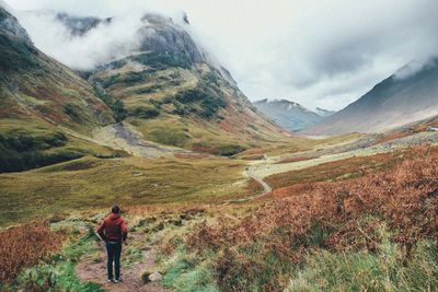 Rear view of woman walking on mountain road against sky
