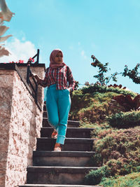 Low angle view of woman on staircase against sky