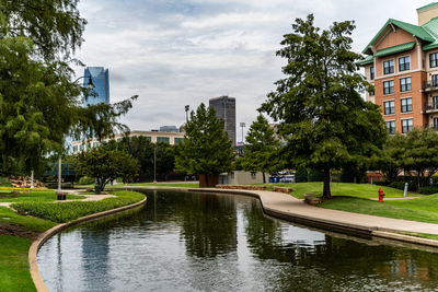 Canal by buildings against sky in city