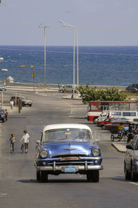 People on car by sea against clear sky