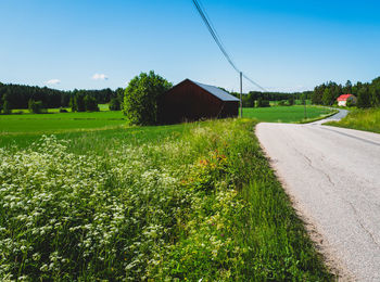 Road amidst field against clear sky