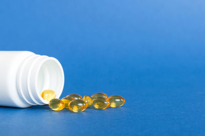 Close-up of pills spilling from bottle on blue background