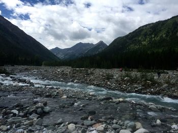 Scenic view of river by mountains against sky